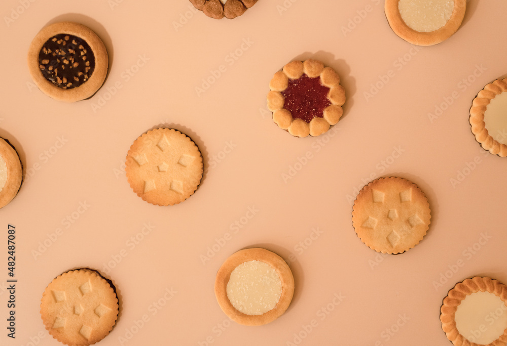 Different sugar strawberry, coconut and chocolate cookies pattern. Tasty freshly baked biscuits isolated on beige background. Flat lay, top view. 