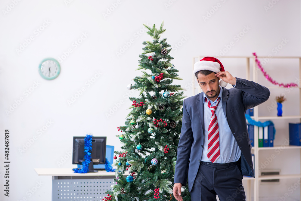Young male employee celebrating Christmas at workplace Young male employee celebrating Christmas at workplace