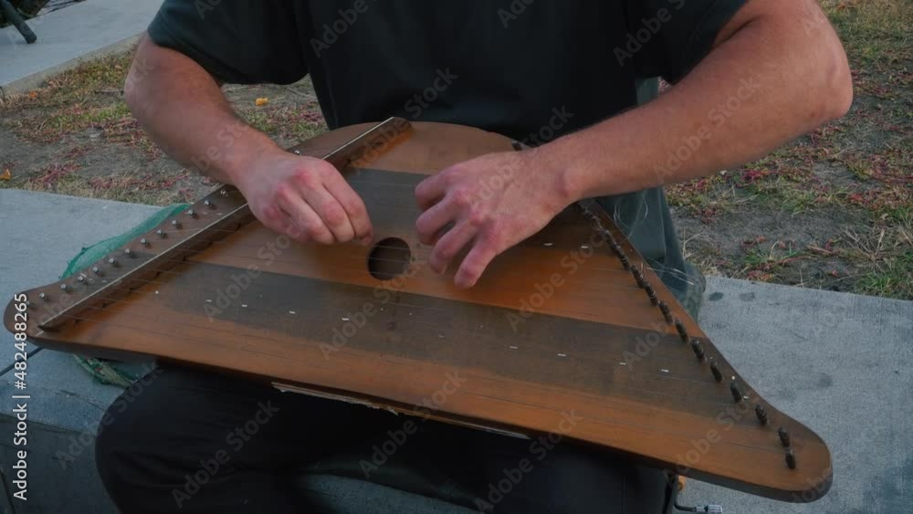 Musician hands beat the strings rhythmically. A man holds gusli on his lap and plays. Soft daylight. Close-up. Musician hands beat the strings rhythmically. A man holds gusli on his lap and plays. Soft daylight. Close-up.