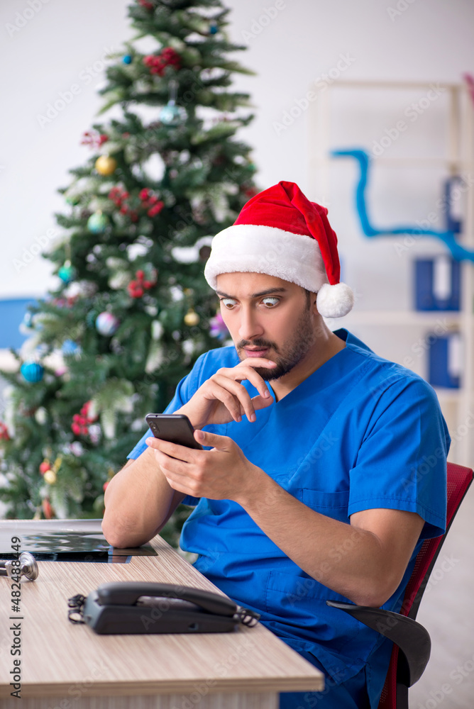 Fototapeta premium Young male doctor celebrating Christmas at the hospital