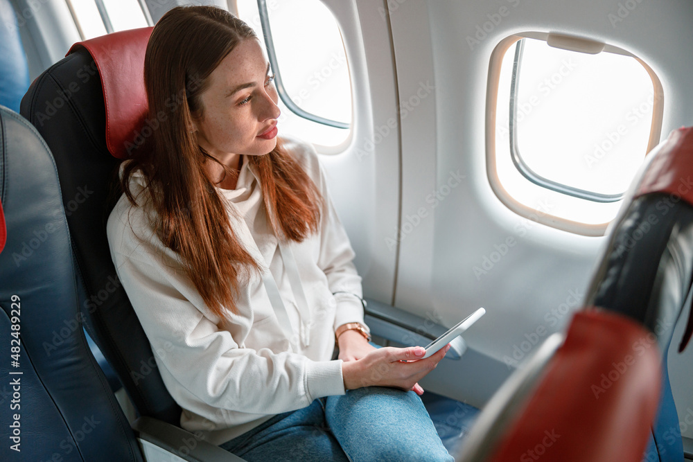 Young woman using mobile phone in airplane Young woman using mobile phone in airplane
