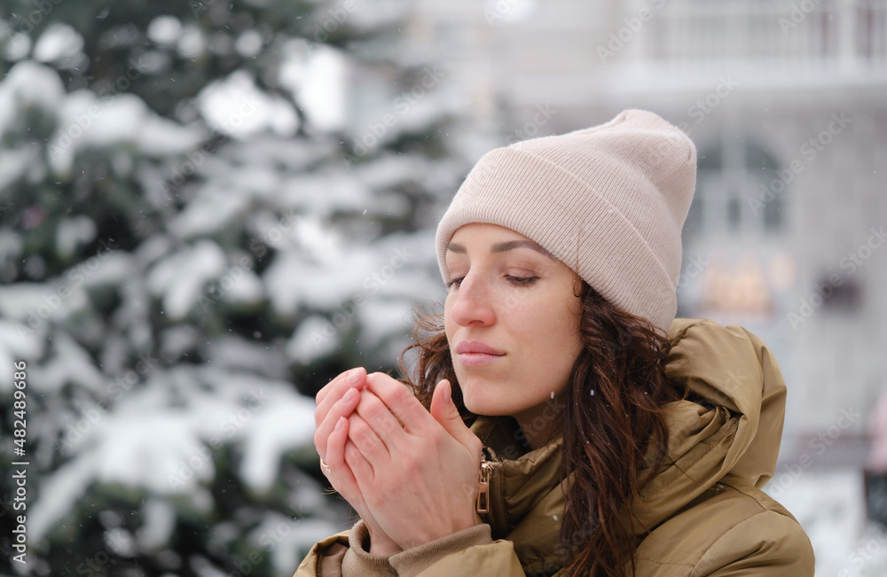 Happy middle age woman warming hands in the city outdoors. Relaxed emotional person walking in winter urban area in a moment, slow living, sincere authentic life, filling cold, frozen Happy middle age woman warming hands in the city outdoors. Relaxed emotional person walking in winter urban area in a moment, slow living, sincere authentic life, filling cold, frozen