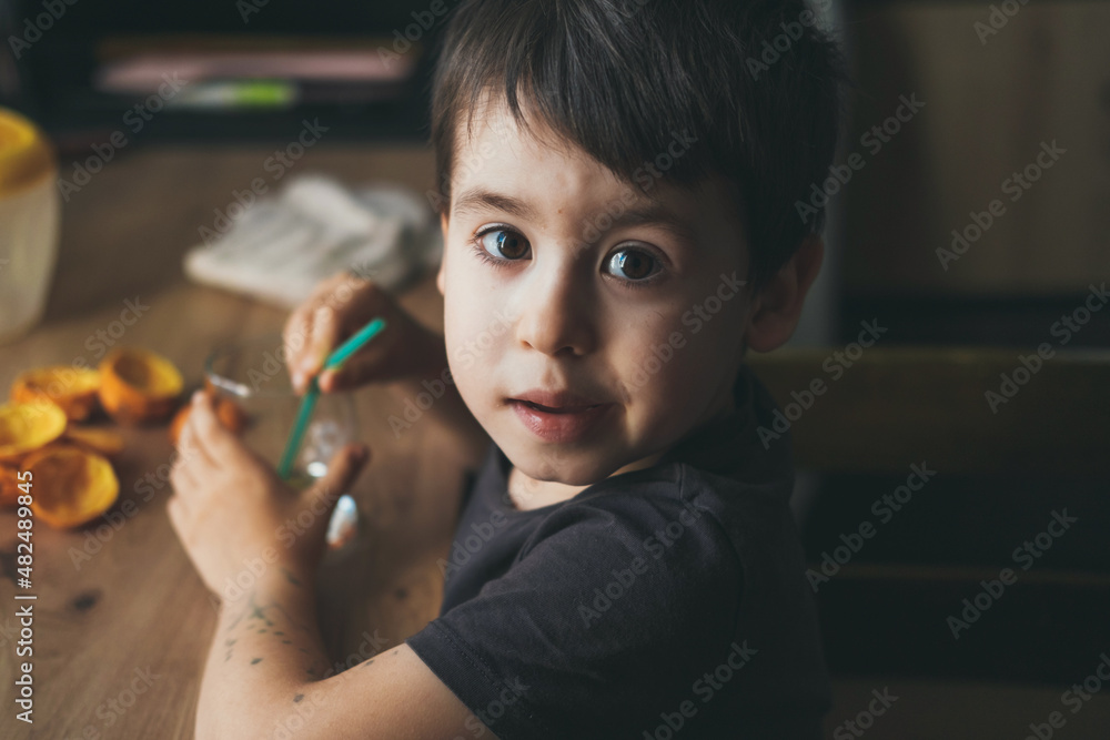 Top view of a boy looking up at the camera while holding a glass of juice. Healthy drink. Top view of a boy looking up at the camera while holding a glass of juice. Healthy drink.