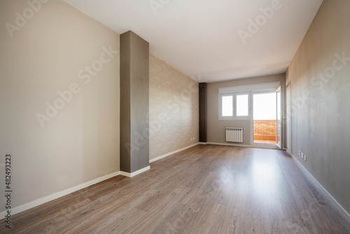 Empty living room with access to a terrace with brick walls and aluminum radiator next to it