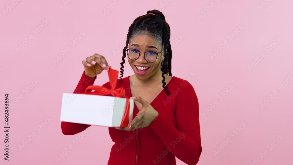 Young african american girl in red clothes holding a white box with red ribbon. Birthday gift Young african american girl in red clothes holding a white box with red ribbon. Birthday gift