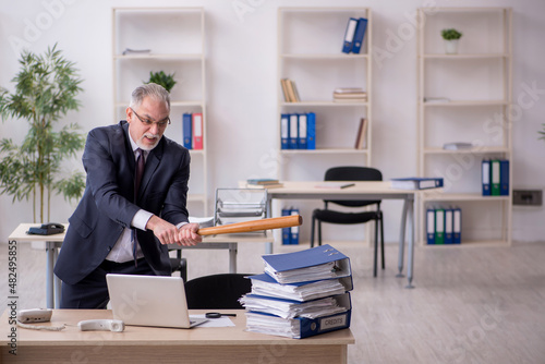 Old male employee unhappy with excessive work in the office