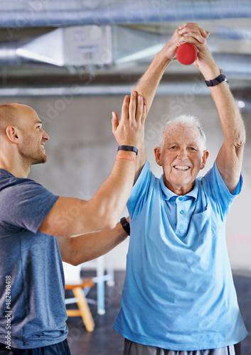 You're getting there. Shot of a physiotherapist helping a senior man with weights. photo