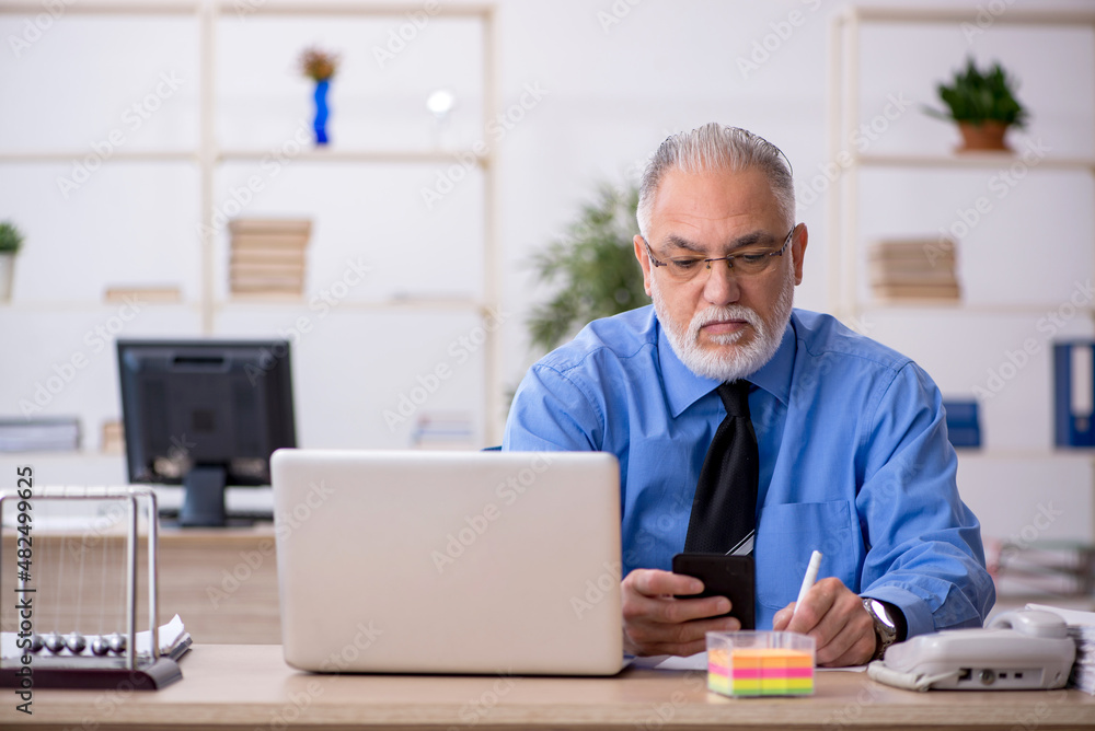 Old male bookkeeper working in the office Old male bookkeeper working in the office