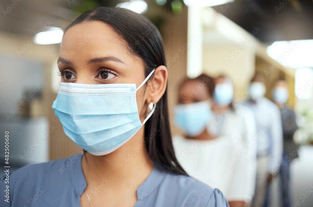 Practicing caution. Cropped shot of an attractive young businesswoman wearing a mask while standing at the head of a queue in her office.