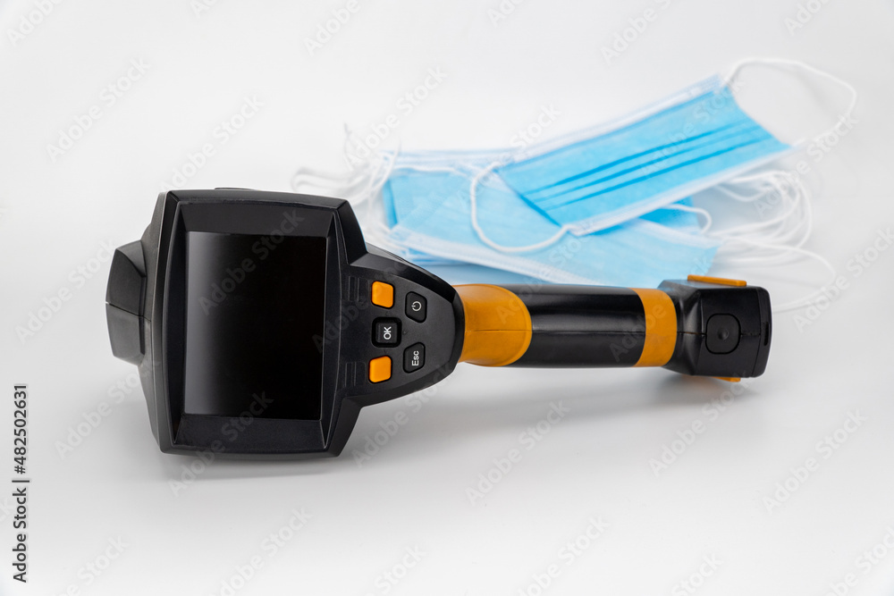 thermal imager and medical masks on a white background. temperature control. body temperature measuring device and virus protection. thermal imager and medical masks on a white background. temperature control. body temperature measuring device and virus protection.
