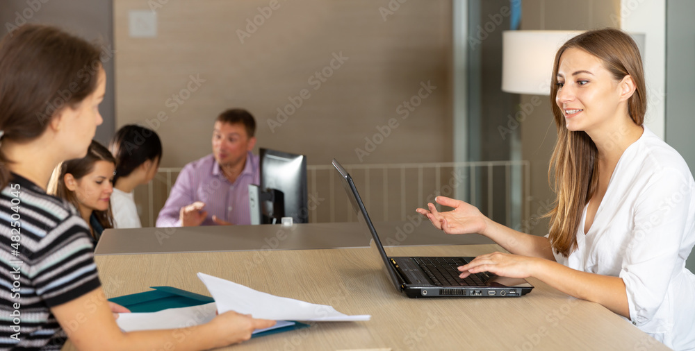 Two women negotiating at table in office