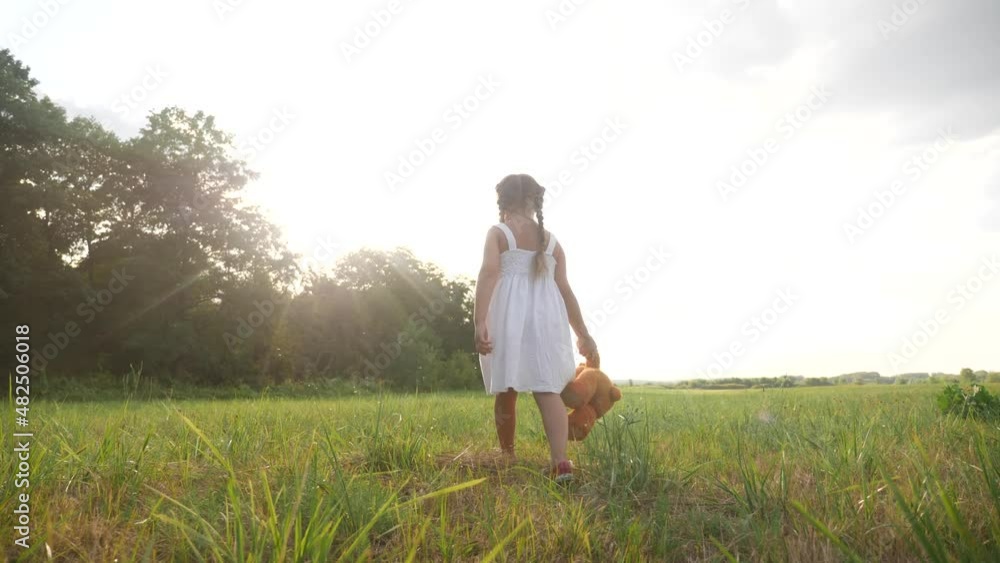 little kid girl walk with a teddy bear toy in the park in nature. childhood dream concept. smiling kid child walk with favorite toy teddy bear dream of happiness in a green park outdoor lifestyle little kid girl walk with a teddy bear toy in the park in nature. childhood dream concept. smiling kid child walk with favorite toy teddy bear dream of happiness in a green park outdoor lifestyle