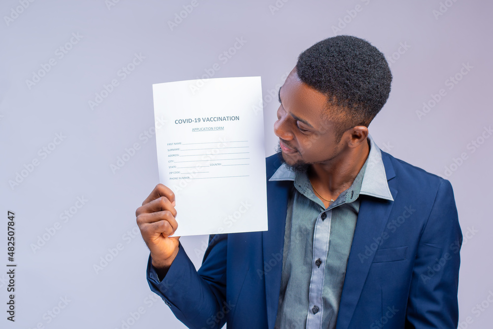 handsome man african doctor looking at the covid vaccination on form in his hand handsome man african doctor looking at the covid vaccination on form in his hand