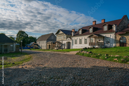 View of the main street of Izborsk Pechorskaya Street with old traditional merchant estates and a paved road on a summer day, Izborsk, Pskov region, Russia