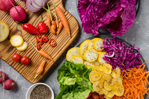 wooden board with fresh, eco, organic vegetables on gray background