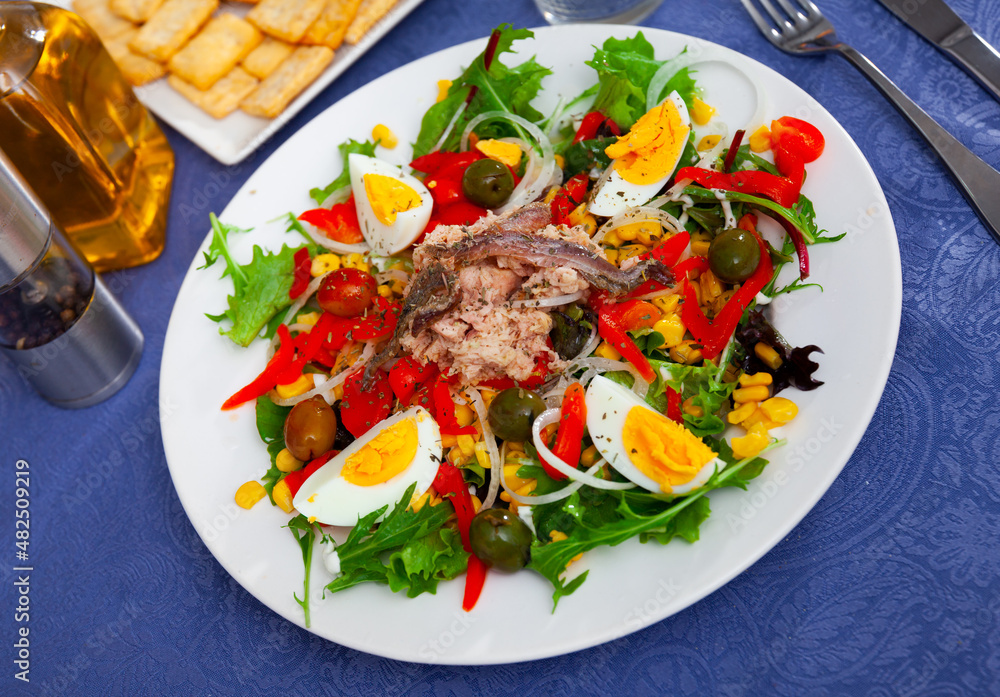 Just prepared fresh anchovy, olive, boiled egg, pepper, onion salad on table.