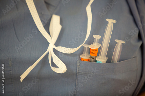 Syringes in shirt pocket of scrubs worn by nurse