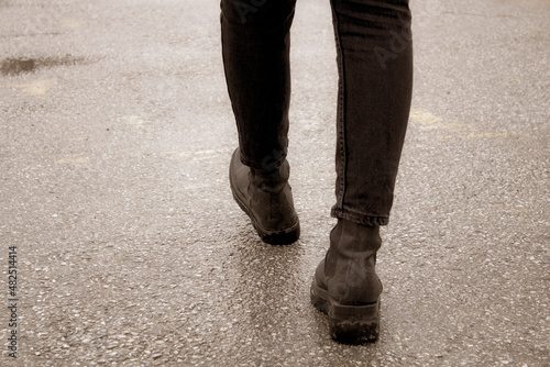 Walking in the snow. Close up of woman shoes Walking on the road. Woman boots walking copy space concept. Close up of black leather boots in cold temperature.