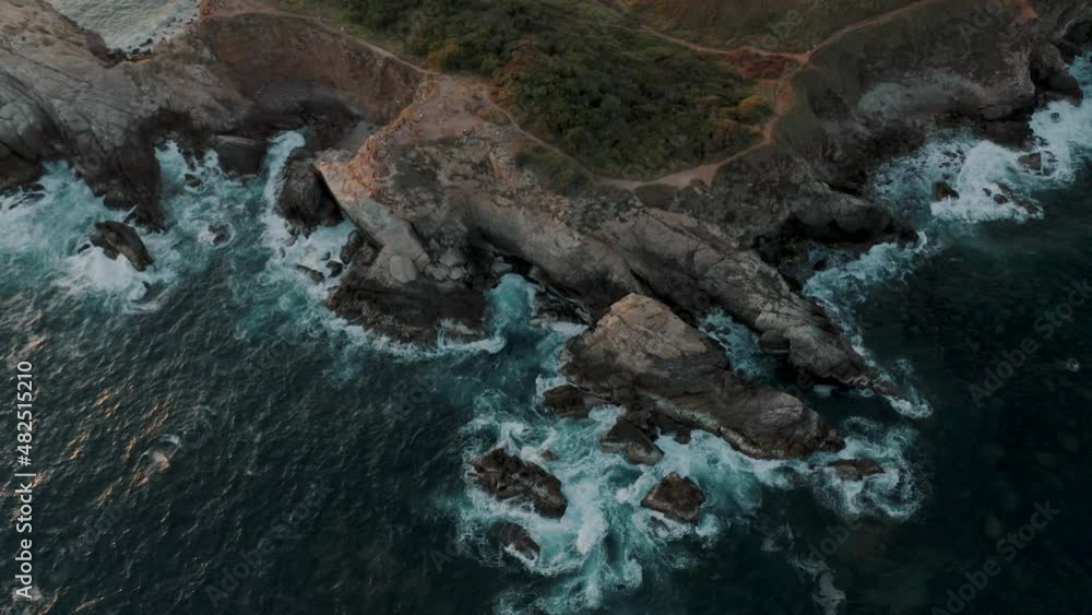 Bird's eye view of waves crashing the cliff on the Mazunte beach in Oaxaca, Mexico. View of Punta Cometa cliffs in the oaxacan coast. Bird's eye view of waves crashing the cliff on the Mazunte beach in Oaxaca, Mexico. View of Punta Cometa cliffs in the oaxacan coast.
