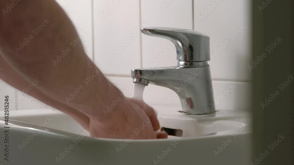 Man washing his hands under a running faucet. Close up Man washing his hands under a running faucet. Close up