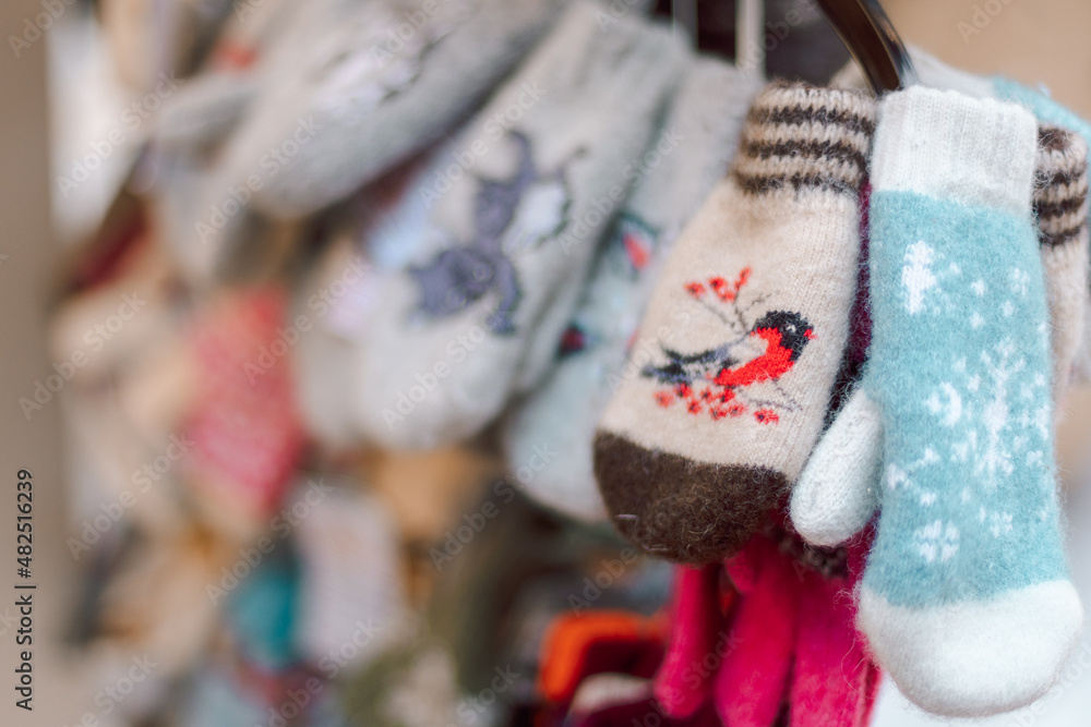 Christmas decoration at the New Year's fair. Winter knitted mittens for hands with bullfinches birds, selective focus. High quality photo