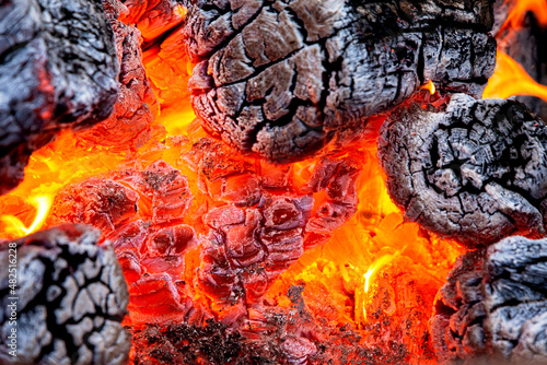 Close up og orange smoldering embers and charred logs in a firepit