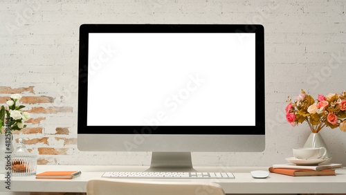Modern office desk with pc desktop computer on table over white brick wall.