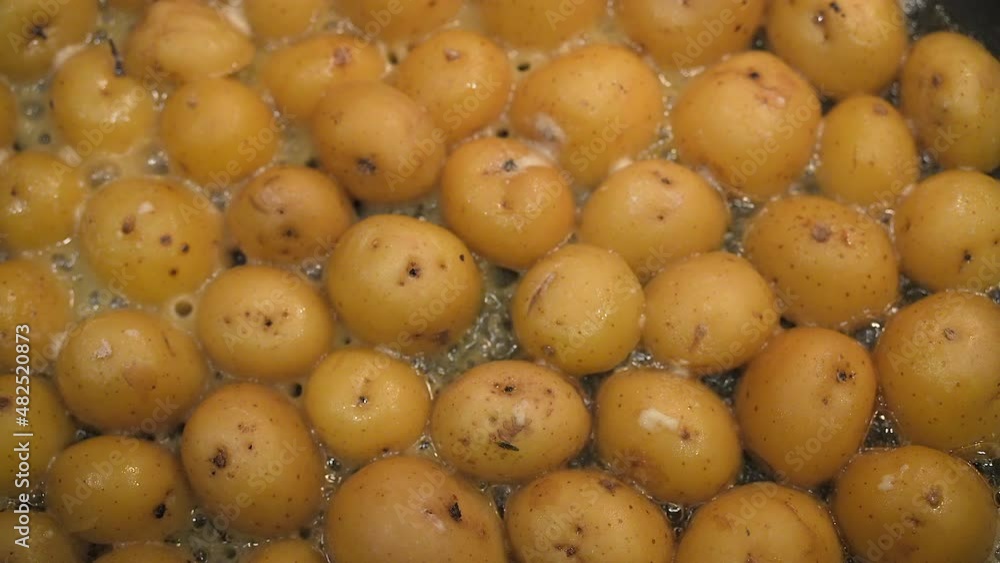 Organic potatoes boiling in an iron skillet on the stove - straight down sliding view Organic potatoes boiling in an iron skillet on the stove - straight down sliding view