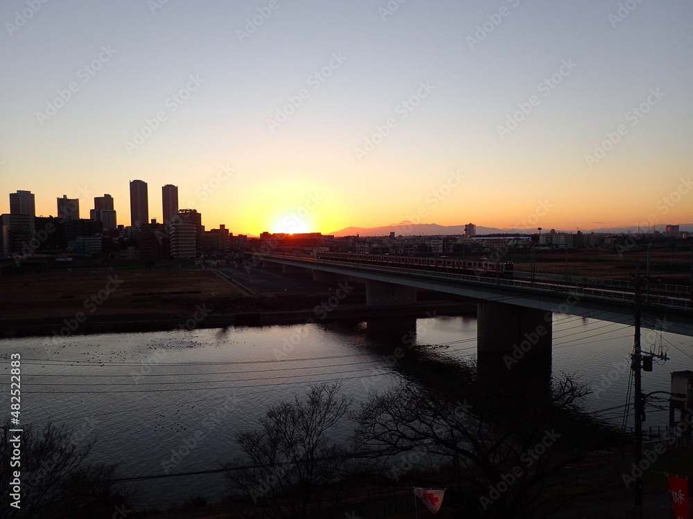 夕陽の多摩川を渡る都会の電車