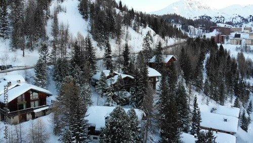 Drone shot of a snowy chalet with mountain backdrop. Filmed in French Alps La Plagne France photo