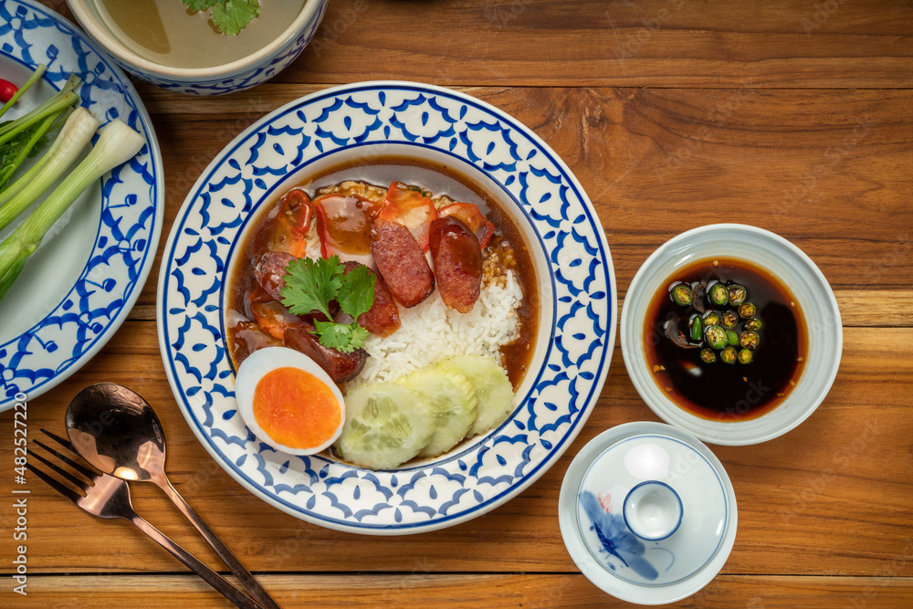 Rice with red roasted pork with sauce and Egg topped in a white dish on wooden table. Rice with red roasted pork with sauce and Egg topped in a white dish on wooden table.