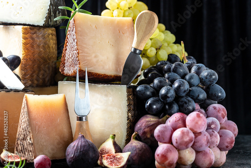 Various kind of cheese, traditional pieces of french, italy and spanish manchego cheese with grapes and figs served on wooden table