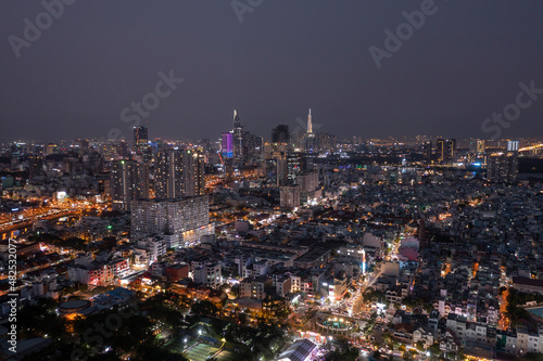 Panoramic drone shot of city at night looking to the city center with busy arterial roads and illuminated buildings.