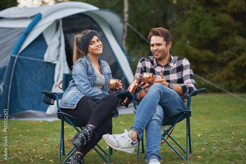Young nice couple sitting on chairs inf front of tent on camping © Kalim