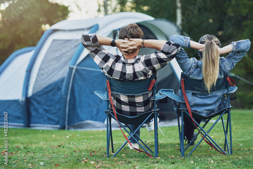 Young nice couple sitting on chairs inf front of tent on camping