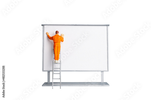Miniature people Painter holding a brush at The front of a whiteboard isolated on white background with clipping path