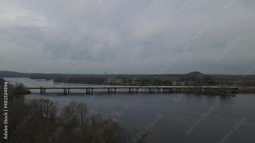 Autumn view of bridge over river in autumn. Many utility towers seen on each side of river. with traffic and lots of power lines. Backwaters seen through the bare tree branches. Autumn view of bridge over river in autumn. Many utility towers seen on each side of river. with traffic and lots of power lines. Backwaters seen through the bare tree branches.