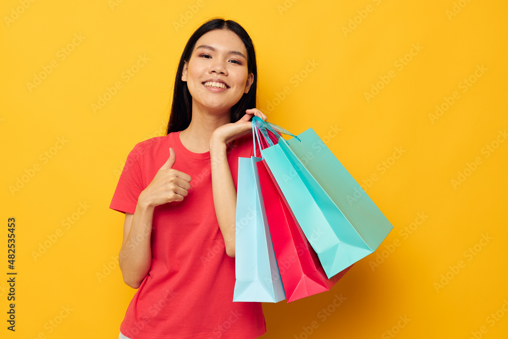 woman with Asian appearance shopping bags in red t-shirt isolated background unaltered