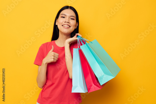 woman with Asian appearance shopping bags in red t-shirt isolated background unaltered