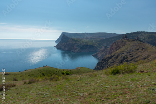 Mountains illuminated sea Balaclava. Light atmospheric spring landscape. View of high cliffs with green trees, blue sky, solar reflections. The concept of travel, active recreation, relaxation, walks