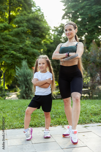 Sportive mom and little daughter posing in the park