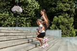 Active family concept. Mom with little daughter run by the stairs outdoors