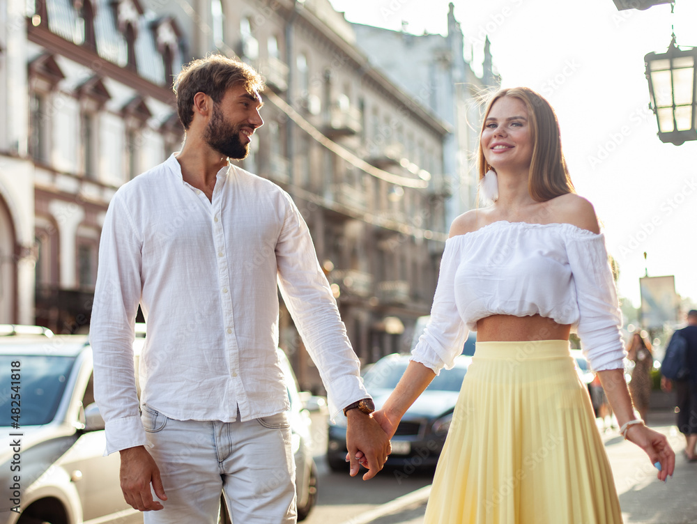 Fototapeta premium Young loving cheerful couple walking in the city