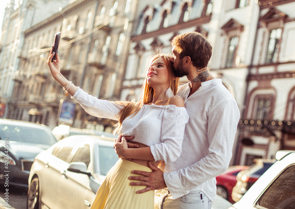 Young couple in love makes selfie on smartphone in the city. Romantic love concept Young couple in love makes selfie on smartphone in the city. Romantic love concept