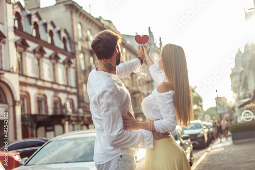 Young couple in love holding a red heart showing their love in the city