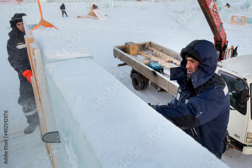 Worker cuts ice panel with gasoline saw