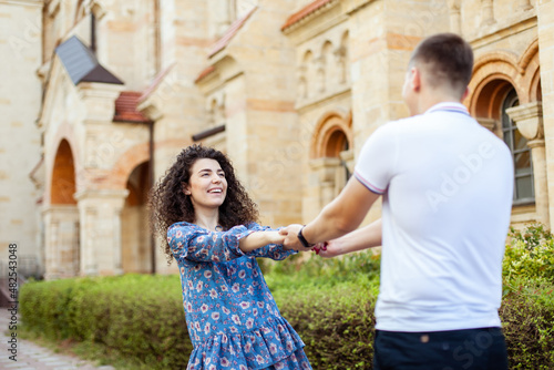 Young couple is whirling hold hands. Having fun outdoors