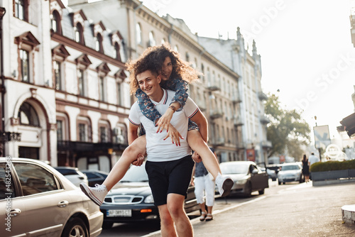 Couple in love. Man carrying girl on his back in the street. Smiling man with beautiful young woman, ride piggyback, having fun together. Relationship concept. © splitov27