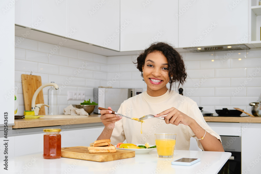 Smiling african american woman having traditional breakfast with fried egg and fresh vegetables Smiling african american woman having traditional breakfast with fried egg and fresh vegetables