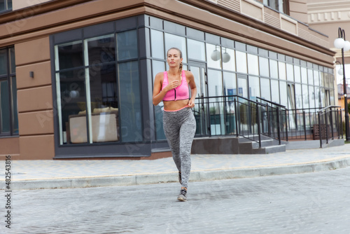 Young woman in overalls runs on in sports clothes outdoors